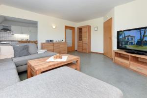 ein Wohnzimmer mit einem Sofa und einem Flachbild-TV in der Unterkunft Ferienwohnung Deichblick in Bensersiel