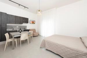 a bedroom with a bed and a table and a kitchen at Residence OndaMare in Cervia +19 photos