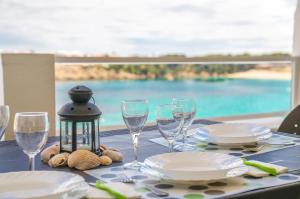 a table with plates and wine glasses and a view of the ocean at White Sands 306 in Arenal d'en Castell