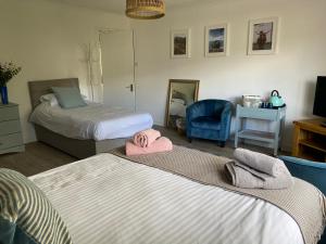 1 dormitorio con 2 camas y silla azul en Braemar House, en Fort William