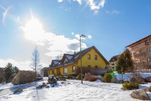 een geel huis in de sneeuw met de zon erachter bij Apartmány Snežienka in Stary Smokovec