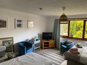 a bedroom with a bed and two chairs and a television at Braemar House in Fort William