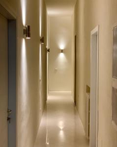 un couloir avec une porte blanche éclairée dans l'établissement HABITARE Lecce & Salento, à Lecce