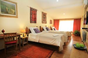 Silk Road Hotel في يريفان: غرفة في الفندق مع سريرين وطاولة جانبية
