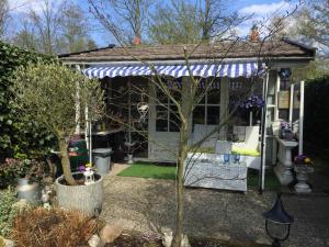 a small cottage with a blue and white pergola at B&B Het Tuinhuisje in Enschede