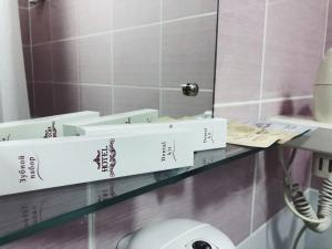 Baño con cajas en un estante frente a un espejo en Italmas Hotel, en Izhevsk