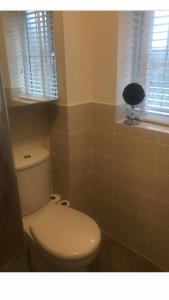 a bathroom with a white toilet and a window at Double room with en-suite. Central for North West in Rainhull