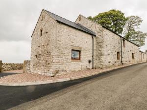 Un antiguo edificio de piedra al costado de una carretera en The Haybarn, en Ashbourne