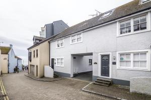 a white building with a black door on a street at Harry's - 2 Bedroom Holiday Home - Tenby in Tenby