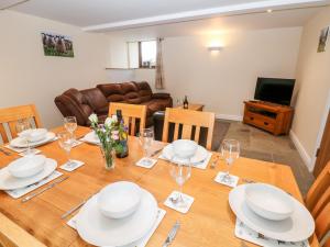 a dining room with a wooden table with plates and wine glasses at The Haybarn in Ashbourne