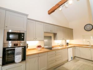 a kitchen with white cabinets and a clock on the wall at The Haybarn in Ashbourne