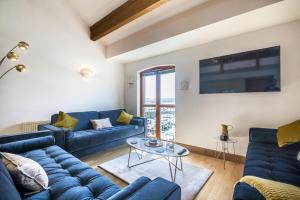a living room with blue couches and a tv at Marina View - 3 Bedroom Apartment - Milford Marina in Milford Haven