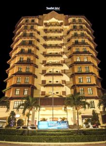 een groot gebouw met een bord ervoor bij Travellers Suites Serviced Apartments in Medan