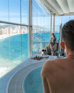 
a man sitting on a balcony looking out at the ocean at Hotel Boutique Villa Venecia in Benidorm
