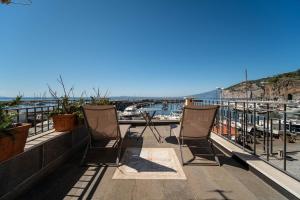 3 chaises assises sur un balcon donnant sur le port dans l'établissement Casa Nori, à Piano di Sorrento