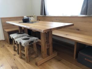 a wooden table with a bench and a table and stool at Renovated 3 Rooms Apartment in Ruschein near Laax in Ruschein