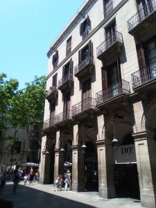 un grand bâtiment avec des personnes qui marchent devant lui dans l'établissement Colom Apartments, à Barcelone