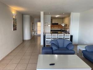 a living room with two blue couches and a kitchen at Sorgente 305 in Umdloti