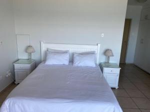 a bedroom with a white bed with two lamps at Sorgente 305 in Umdloti