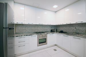 a white kitchen with white cabinets and appliances at KeyHost - Large 1BR Apartment near Five Hotel JVC - Dubai - K310 in Dubai