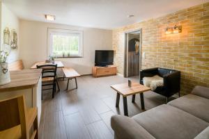 a living room with a couch and a tv at Hotel Hofgut Tiergarten in Aulendorf