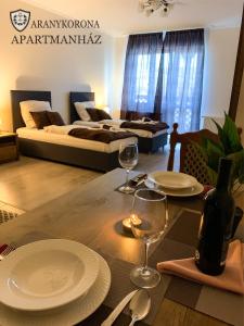 - une table avec des assiettes et des verres à vin dans le salon dans l'établissement Aranykorona Apartmanház, à Miskolc
