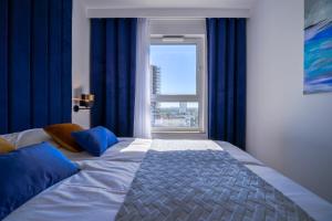 um quarto com uma cama grande com cortinas azuis e uma janela em CITYSTAY Nowa Letnica Gdansk Apartment em Gdansk
