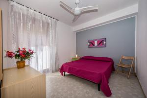 a bedroom with a purple bed and a window at Case Maria in Castellammare del Golfo