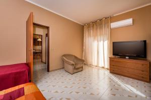 a bedroom with a flat screen tv and a chair at Case Maria in Castellammare del Golfo