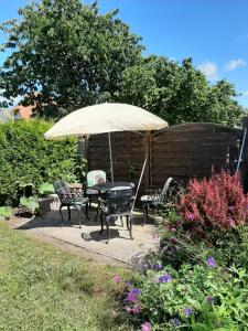 un patio con una mesa y una sombrilla en un jardín en Kleines Ferienhäuschen en Kritzmow