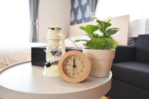 a alarm clock sitting on a table next to a plant at Sasatsuka Fleur Tachibana Hotel Apartment in Tokyo