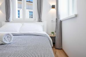 a white bedroom with a bed and a window at Music Apartment By Locap Group in Piran