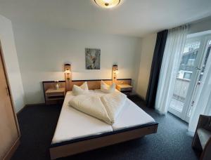 a bedroom with a bed with white sheets and pillows at Ferienwohnungen Germania in Schönau am Königssee