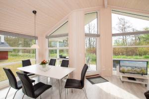 - une salle à manger avec une table, des chaises et des fenêtres dans l'établissement Resort 2 Ocean Cottage A 87, à Großenbrode