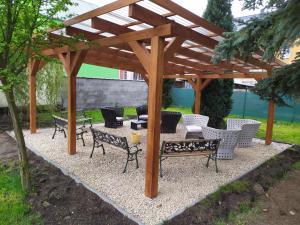 a wooden pergola with chairs and tables under it at Bluestars Home in Karlovy Vary