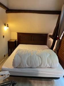 Bett mit weißer Bettwäsche und einem Kopfteil aus Holz in der Unterkunft Le Caux'gîte in Bretteville-du-Grand Caux
