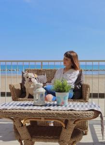 Una donna seduta su una sedia con un cane sulla spiaggia di Nautic Beach Hotel a Rimini