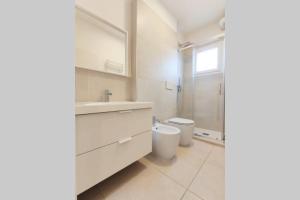 a white bathroom with a sink and a toilet at DELTA D Piazza Marina- 50 MT dal mare - Immobil Relax in Lido di Jesolo
