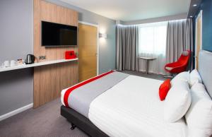 a hotel room with a large bed and a red chair at Holiday Inn Express Ramsgate – Minster by IHG in Minster
