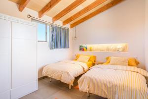 two beds in a room with white walls and wooden ceilings at Son Sunyer in La Aranjasa +18 photos