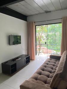 a living room with a couch and a large window at Aconchego e Requinte no Centro in Petrópolis