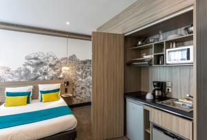 Habitación con cama y cocina con fregadero en Nemea Appart Hotel Paris Levallois, en Levallois-Perret