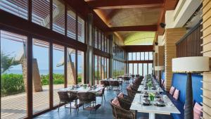 a long dining room with tables and chairs and windows at Crowne Plaza Hailing Island by IHG in Yangjiang