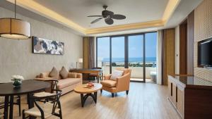 a living room with a couch and chairs and a television at Crowne Plaza Hailing Island by IHG in Yangjiang