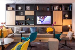 a living room with a couch and a tv at Nemea Appart Hotel Paris Levallois in Levallois-Perret