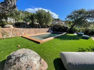 un patio con piscina y pared de piedra en Bel appartement dans hameau calme en Bonifacio