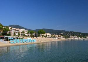 a beach with chairs and people on the beach at Studio 207-Front de mer parking privé in Cavalaire-sur-Mer