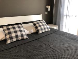 a bed with two checkered pillows on it at Hotel Aplo - Breakfast Experience in Cervia