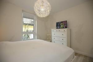 a bedroom with a white bed and a chandelier at Strandvilla Scholle - Dorsch Wohnung 02 in Boltenhagen