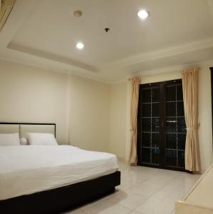 ein Schlafzimmer mit einem großen Bett und einem Fenster in der Unterkunft SUPERBLOCK 3 BEDROOM 103sqm AT MALL in Jakarta